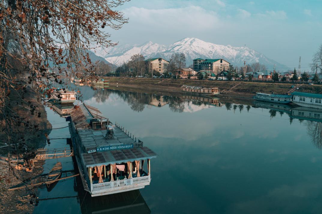 Traditional houseboats floating on Dal Lake with mountains in Srinagar Kashmir
